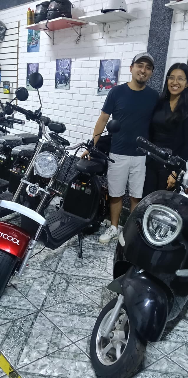 Pareja feliz junto a sus motos ECOOL en el showroom