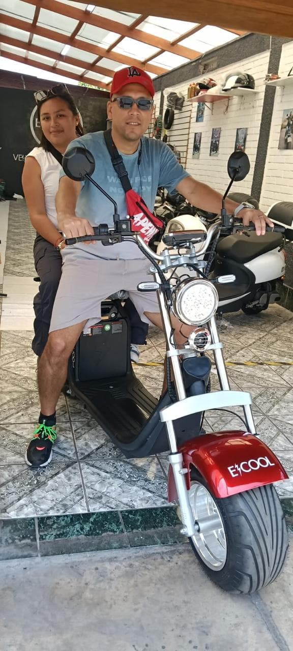 Pareja feliz en su ECOOL chopper roja en el showroom